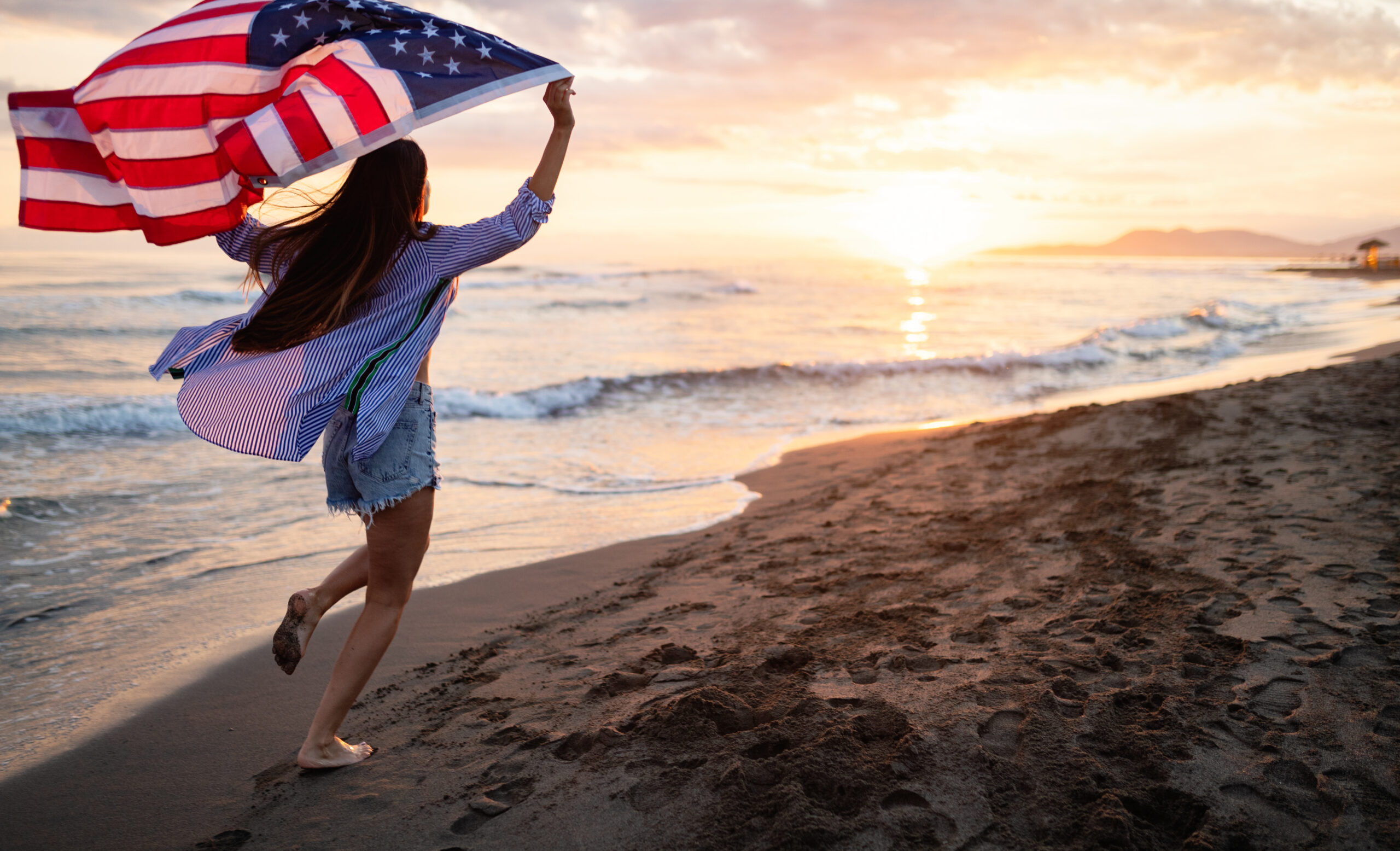 Happy woman running on beach while celebrateing independence day and enjoying freedom in USA