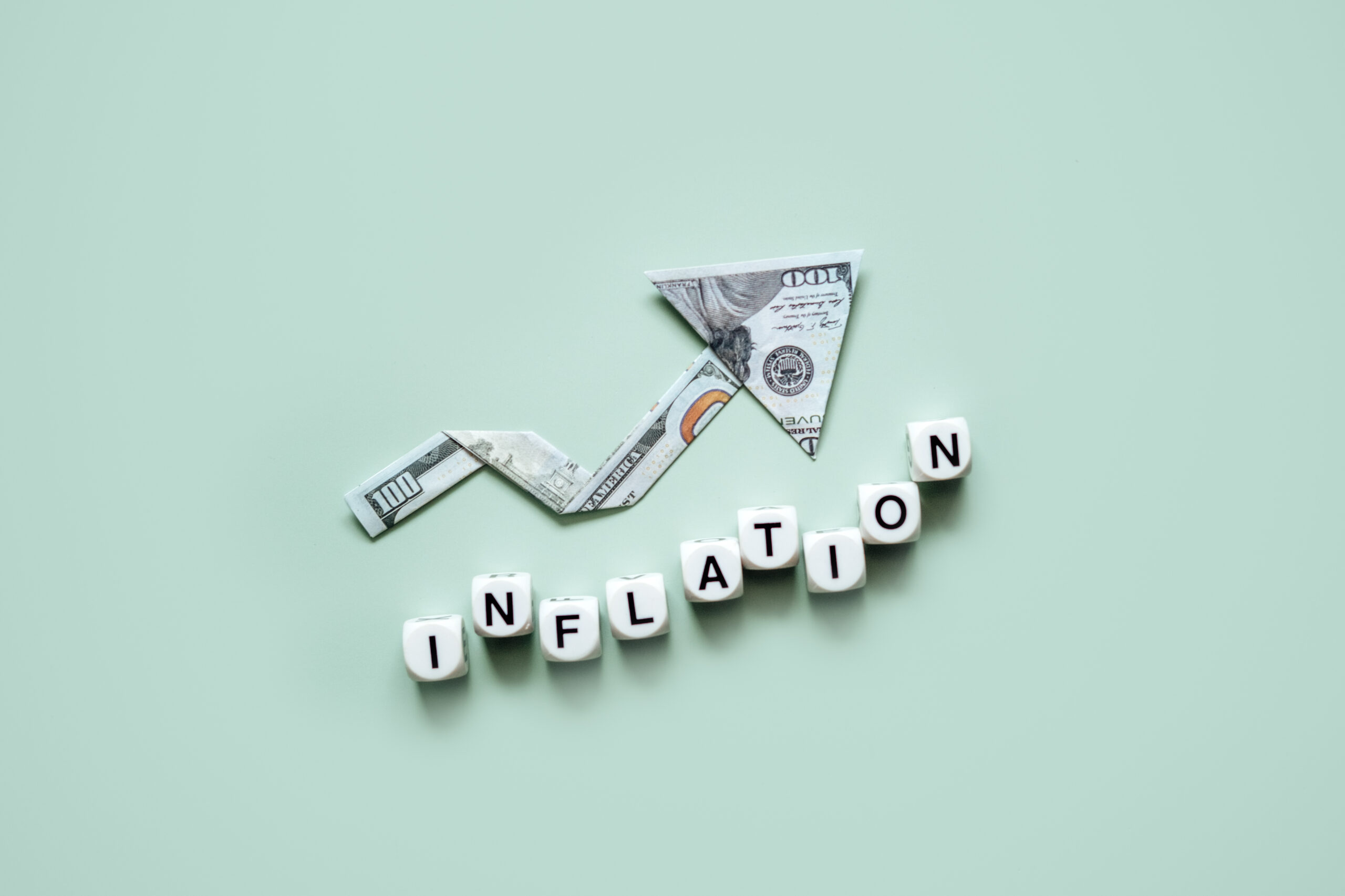 Inflation financial crisis concept. Growing up arrow from dollar banknote and word Inflation on blue background. Rising cost of living